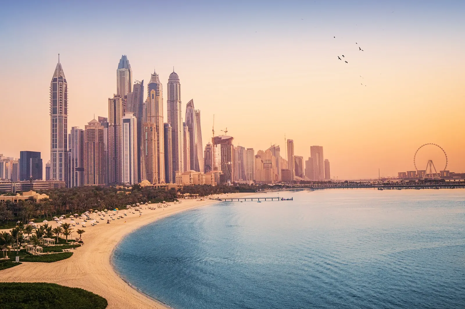 Sunset view of the Dubai Marina, JBR area and the famous Ferris Wheel and golden sand beaches in the Persian Gulf, UAE