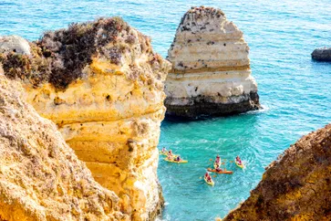 Rotsachtige kustlijn bij Ponta da Piedade met mensen kajaks, vlakbij de stad Lagos, Algarve, Portugal