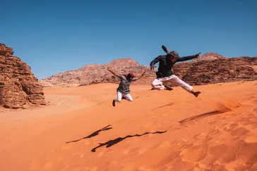 Springen op zandduin, Wadi Rum, Jordanië 