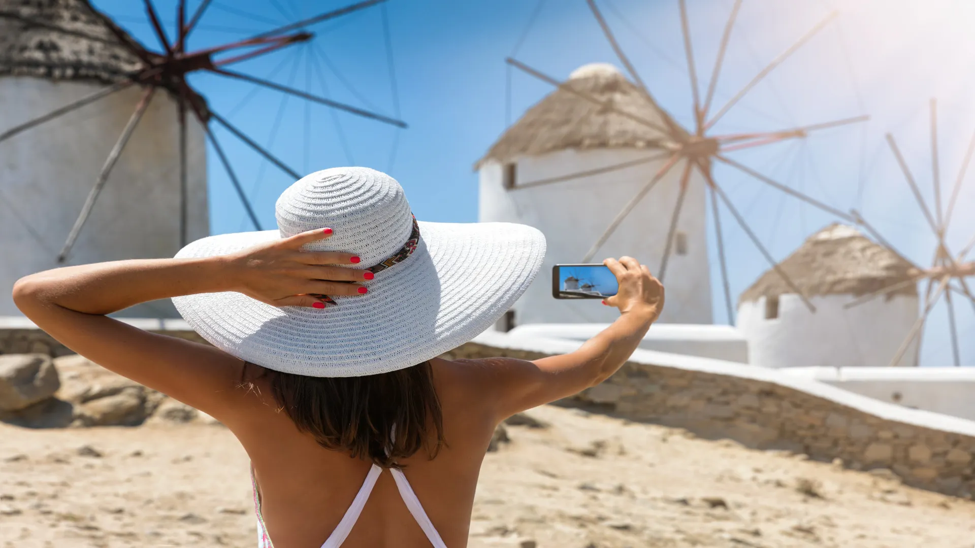 Vrouw met witte hoed, selfie bij molentjes Mykonos, Griekenland