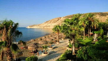 Strand Pissouri met palmbonen, zee, heuvels, strandbedjes met parasol, Cyprus
