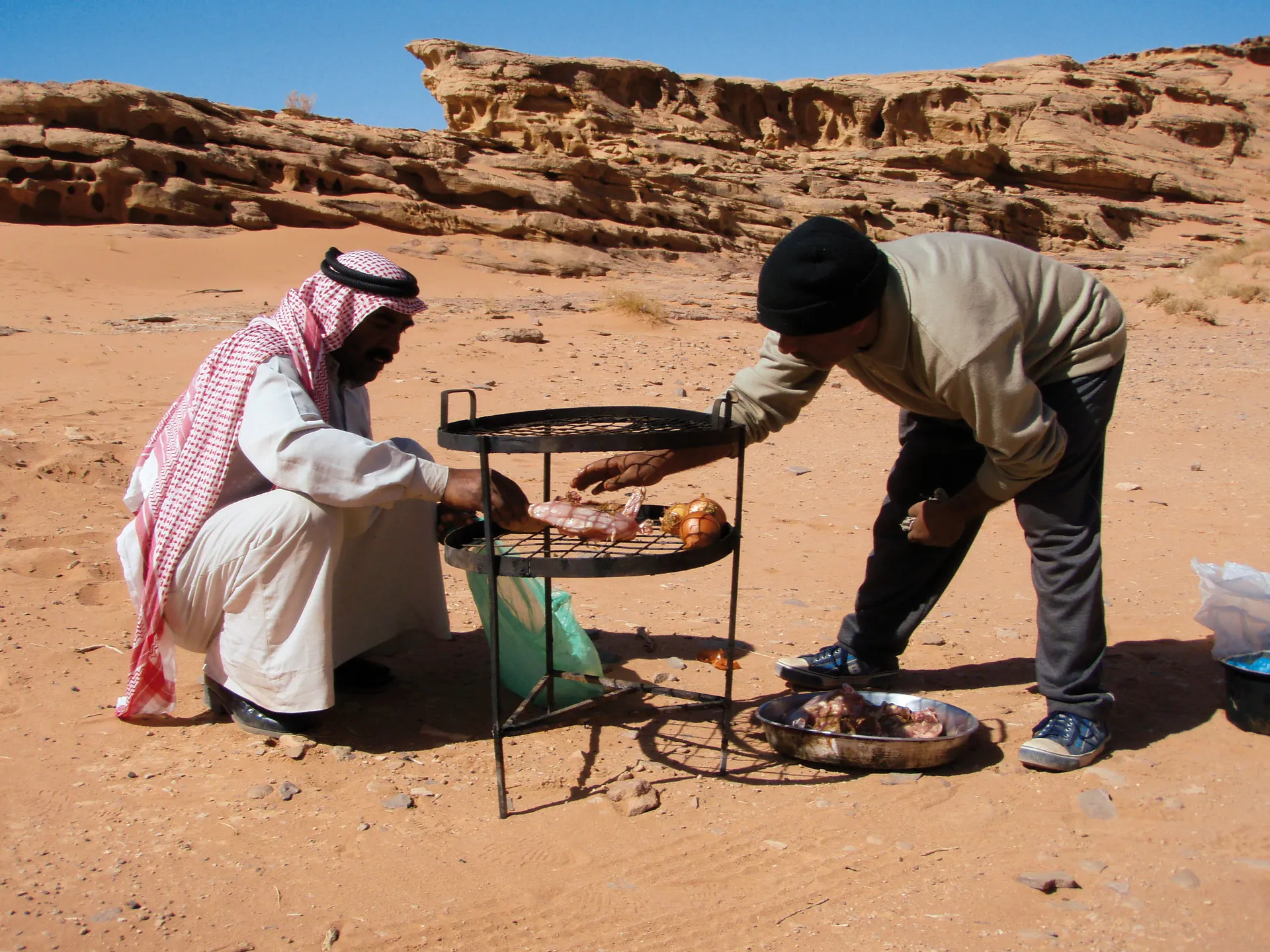 Twee mannen bereiden Zharb voor, een ondergrondse barbecue, Wadi Rum, Jordanië 
