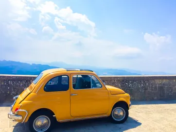 Auto Fiat 500 geel groot met uitzicht Italie
