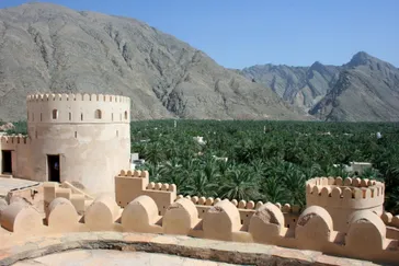 Fort Bahla met palmbomen en bergen op de achtergrond, Oman