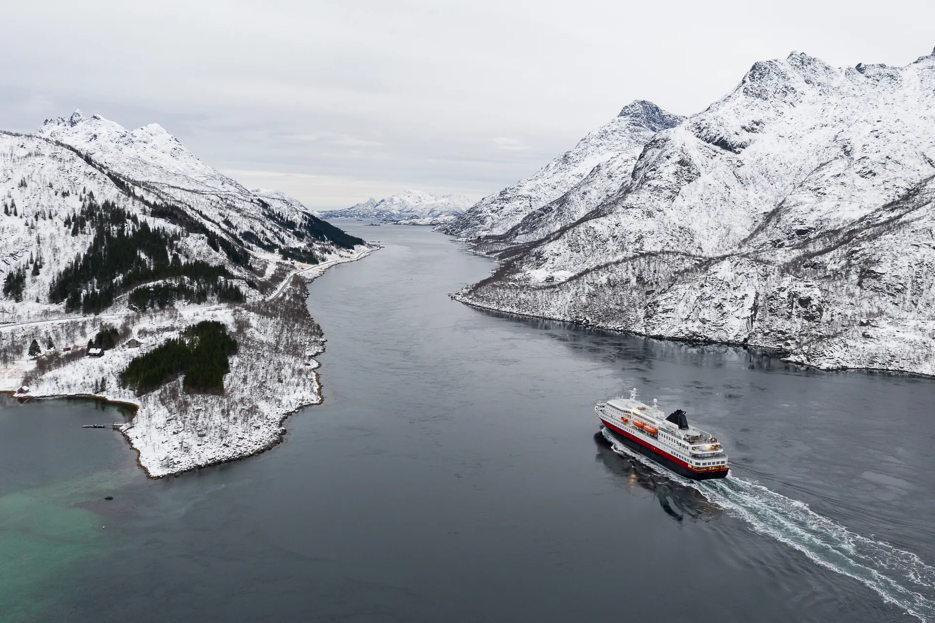 &Olives Noorwegen Aerial view of fjord in cold winter weather with Hurtigruten ferry turist boat on the sea. Lofoten near Trollfjorden