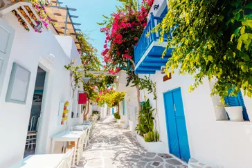 Traditionele Griekse straat met kleurrijke bloemen en blauwe deuren op het eiland Paros, Griekenland