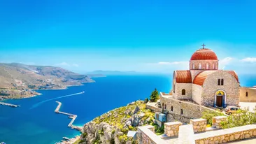 Prachtig uitzicht op de afgelegen kerk met rode daken op de klif van de zee, Griekenland