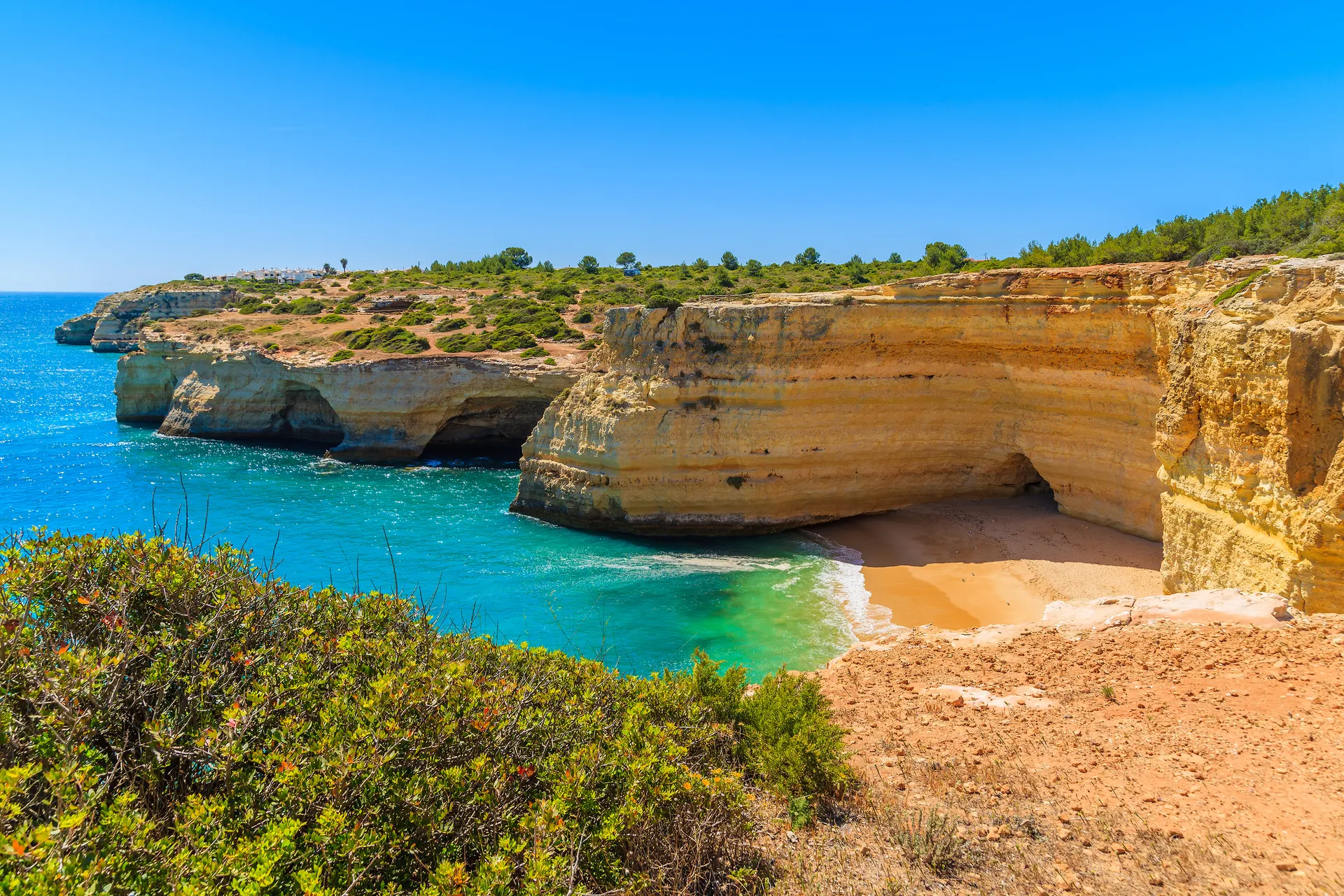 Zandstrand omringd door rotswanden een een kleine grot bij Carvoeiro, Algarve, Portugal