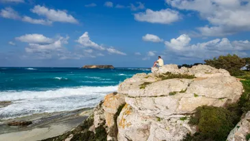 Man zittend op rots en uitkijkend over zee, Akamas, Cyprus