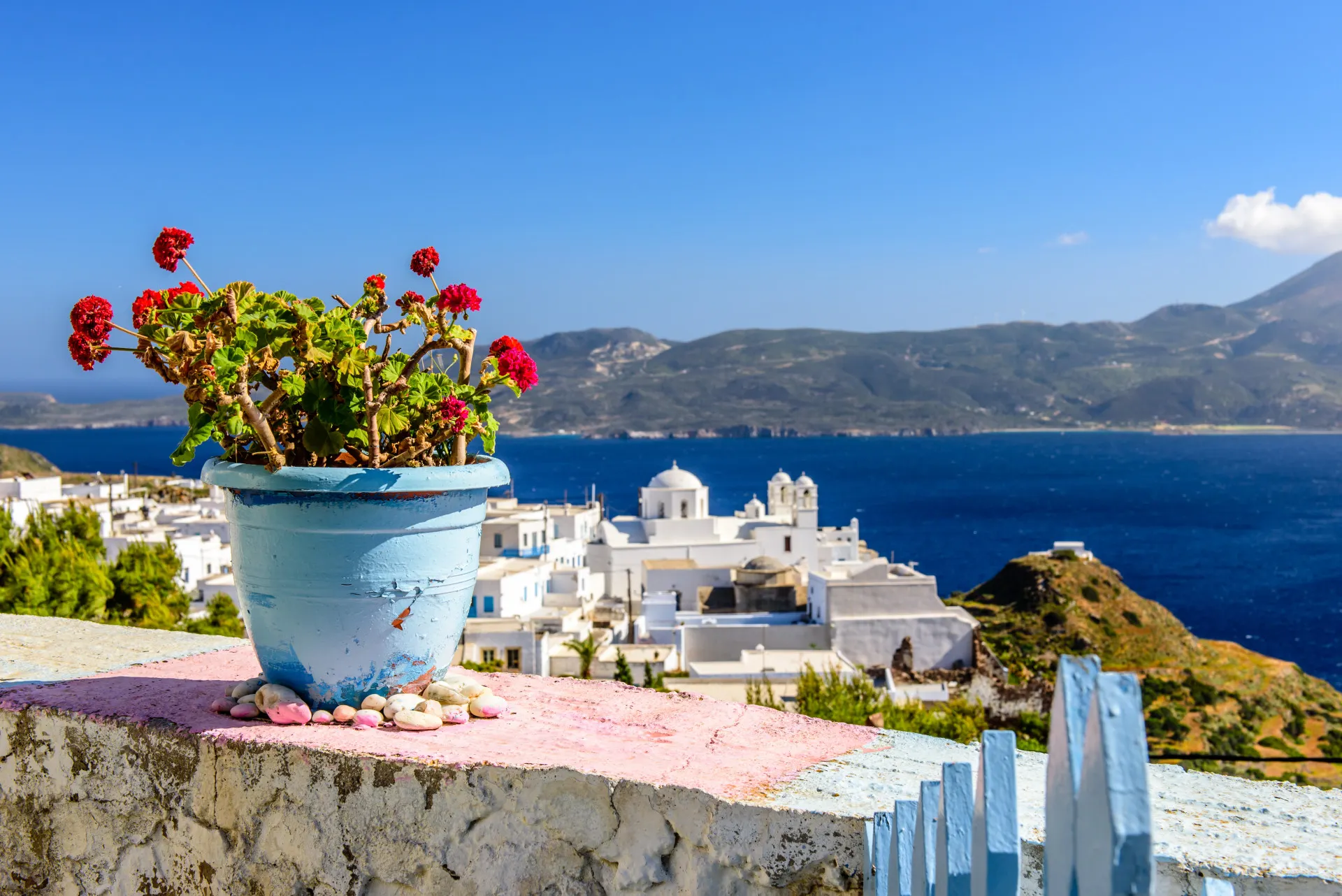 Geranium met uitzicht op dorpje en bergen in Milos Griekenland
