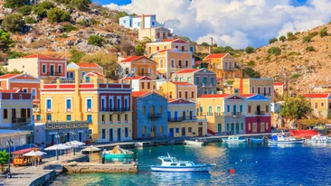 De haven van Symi, Griekenland, gekleurde huisje tegen een heuvel, water en bootjes