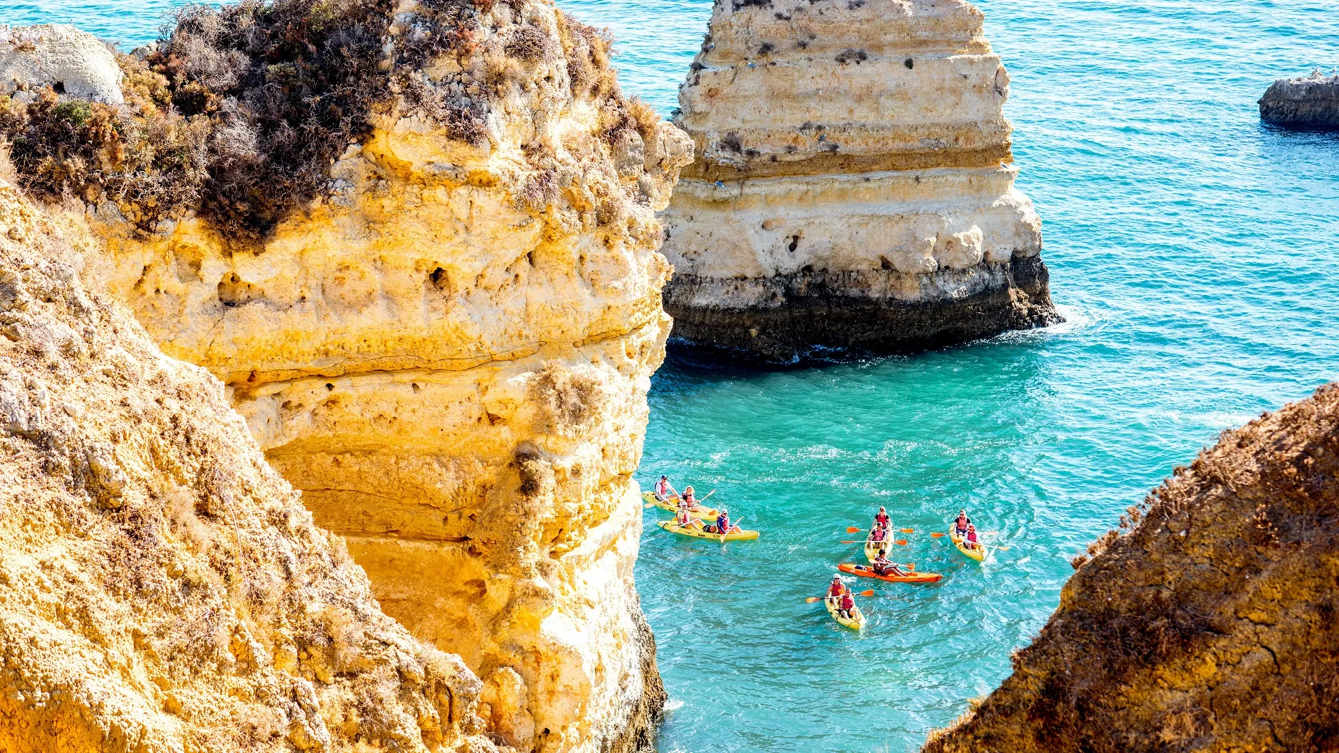 De rotsachtige kustlijn op Ponta da Piedade met mensen die in kajaks dichtbij de stad Lagos in het zuiden van Portugal zwemmen