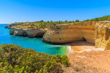 Zandstrand omringd door rotswanden een een kleine grot bij Carvoeiro, Algarve, Portugal