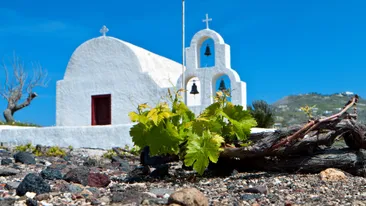 Het zwarte kiezelstrand voor een wit kerkje op Santorini