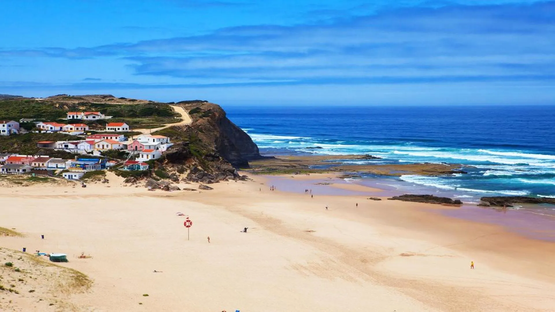Strand met stadje op de achtergrond, Costa Vicentina, Portugal