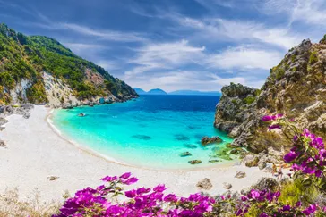 Agiofili strand - Lefkas Griekenland - helderblauw water, strand, paarse bloemen en groene heuvels